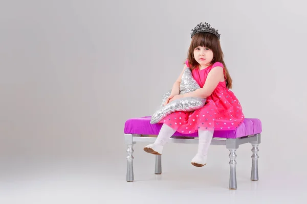 Hermosa niña en vestido de princesa rosa con la corona sentado —  Fotos de Stock