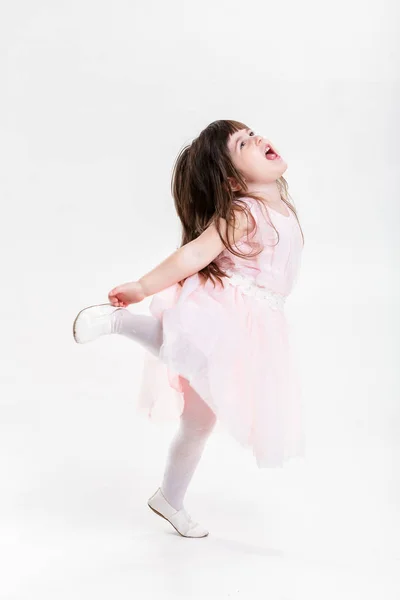 Schöne kleine Mädchen in rosa Prinzessinnenkleid springt vor Freude auf einem — Stockfoto