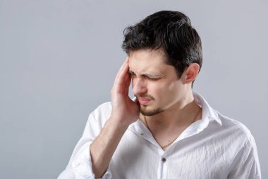 Hayal kırıklığına uğramış genç esmer adam gömlek gri bac üzerinde baş ağrısı ile