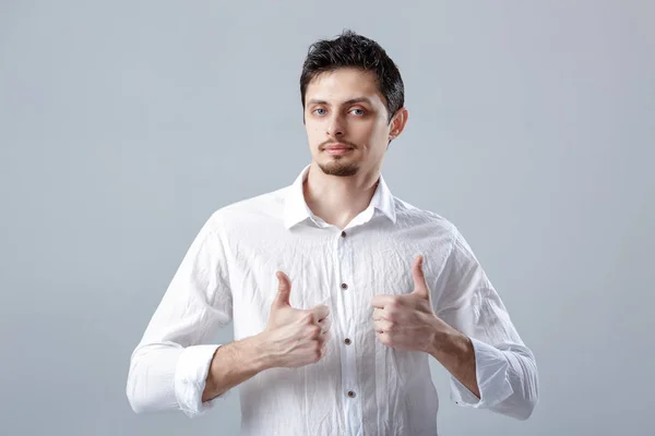Retrato de ahandsom sorrindo homem morena na camisa mostrando polegares — Fotografia de Stock
