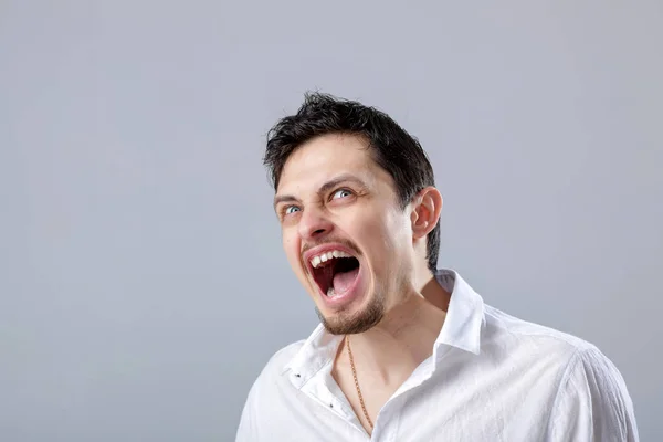 Mérges fiatalember, aki kiabált a szürke háttere fehér ing — Stock Fotó
