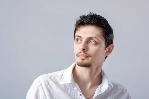 Portrait de beau jeune homme aux cheveux foncés en chemise blanche sur — Photo