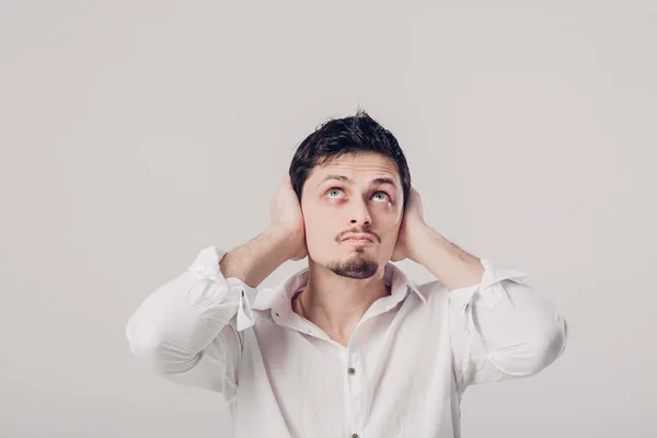 Portrait de jeune homme en chemise couvre ses oreilles avec ses mains ag — Photo