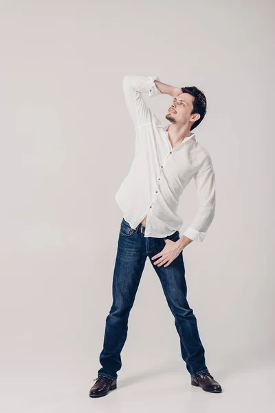 Retrato de joven guapo con pelo oscuro en camisa blanca sobre fondo gris. luz suave — Foto de Stock