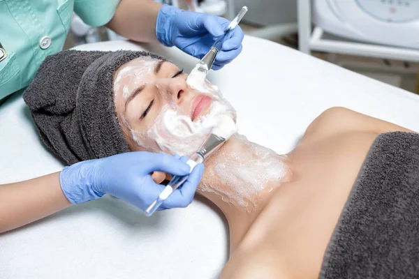 Косметолог наносит маску с кистью на молодую женщину в Спа са — стоковое фото
