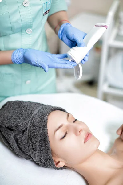 Kosmetyczka stosuje krem do twarzy na młoda kobieta w salonie Spa. COSME — Zdjęcie stockowe