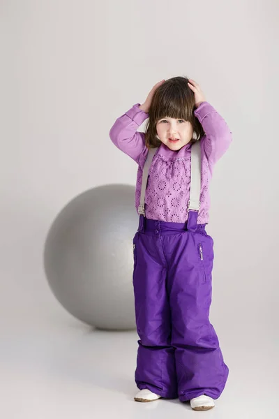 Menina bonito pouco em roupas roxas segurando sua cabeça e grande bola — Fotografia de Stock
