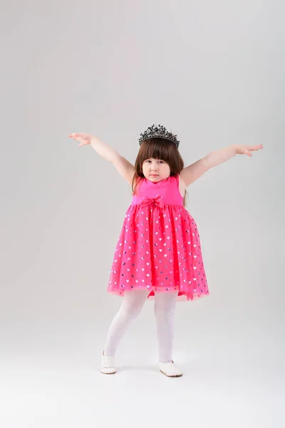 Hermosa niña en vestido de princesa rosa con corona con brazo —  Fotos de Stock