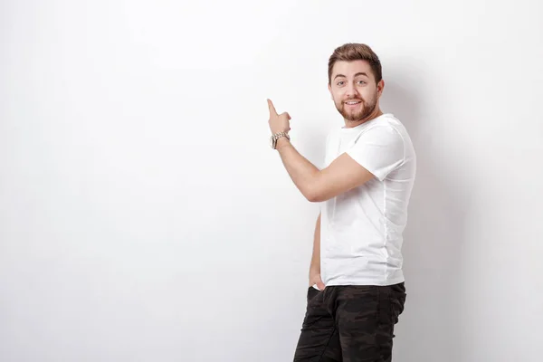 Bel homme avec barbe pointant l'espace de copie. jeune homme en t-shir — Photo