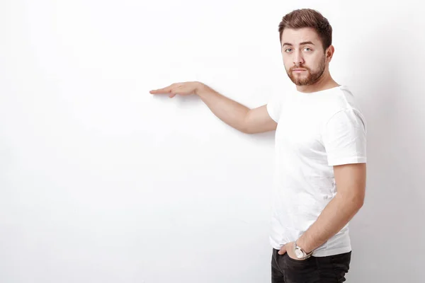 Un hombre guapo con barba apuntando al espacio de copia. joven en t-shir — Foto de Stock