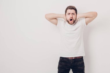 Siyah saçlı ve sakallı t-shirt ile kızgın genç adam bağırır bir