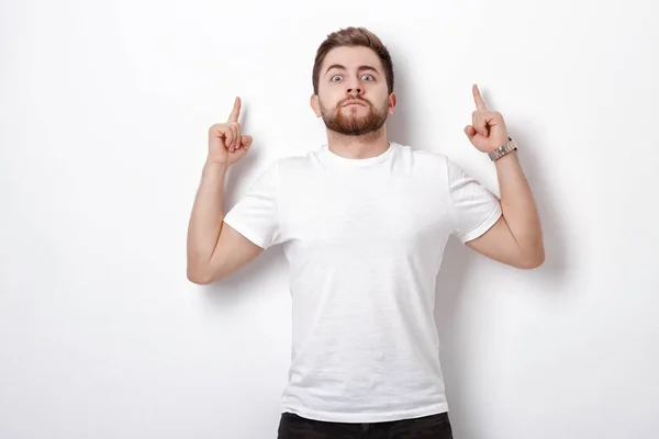 Un hombre guapo con barba apuntando hacia arriba. joven mirando a la cámara — Foto de Stock