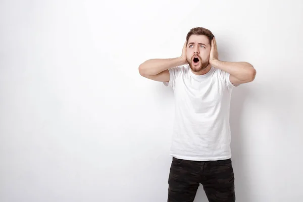 Giovane indignato con i capelli scuri e la barba in t-shirt grida un — Foto Stock