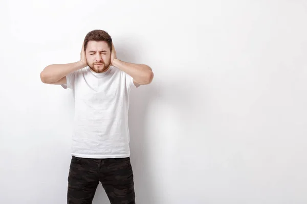 Portrait de jeune Brunet homme en chemise couvre ses oreilles avec les mains — Photo