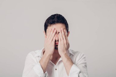 Beyaz tişörtlü adam portresi gr üzerinde elleriyle gözlerini kapatır