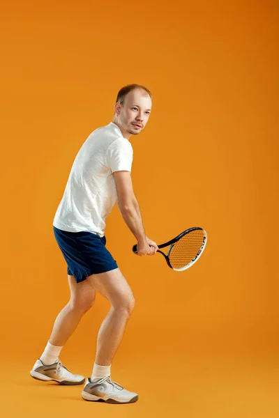 Jovem bonito jogador de tênis masculino joga tênis no backgro amarelo — Fotografia de Stock