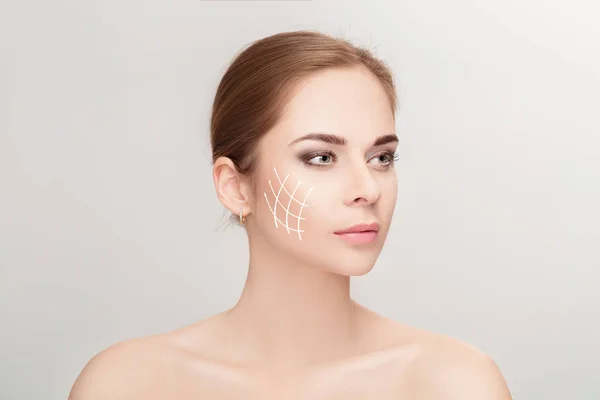 Spa portrait of woman with arrows on her face on grey background