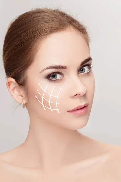 Spa portrait of woman with arrows on her face on grey background — Stock Photo, Image