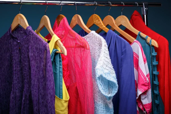 Colorful womens clothes on wood hangers on rack on blue backgrou — Stock Photo, Image