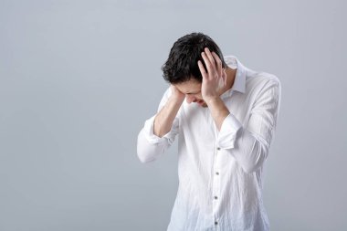 Hayal kırıklığına uğramış genç esmer adam gömlek gri bac üzerinde baş ağrısı ile