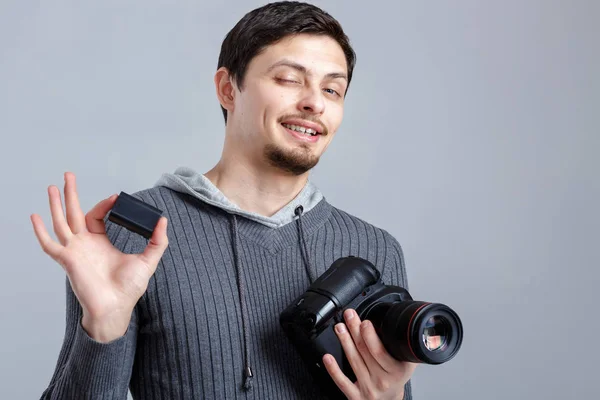Giovane fotografo sorridente in camicia tiene la batteria per DSLR — Foto Stock