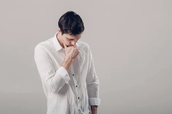 Ritratto di bel giovane uomo pensieroso in camicia bianca su ba grigio — Foto Stock