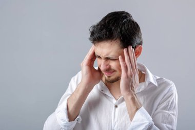 Hayal kırıklığına uğramış genç esmer adam gömlek gri bac üzerinde baş ağrısı ile