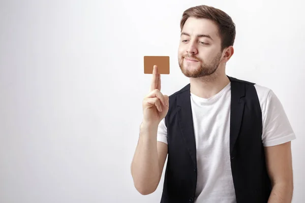 Giovane bell'uomo con barba in camicia bianca e gilet nero che mostra carta di credito in plastica e sorridente — Foto Stock