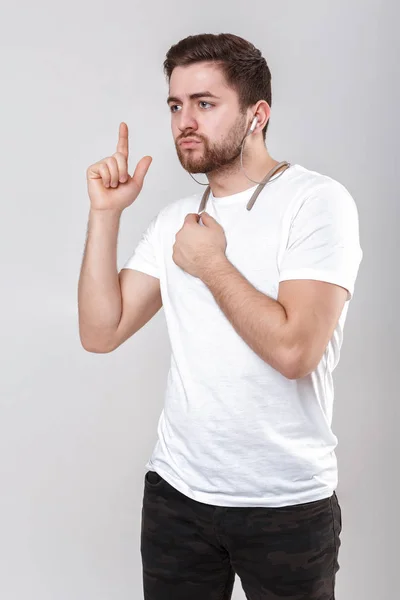 Jonge knappe man met baard in t-shirt luisteren naar muziek op koptelefoon — Stockfoto