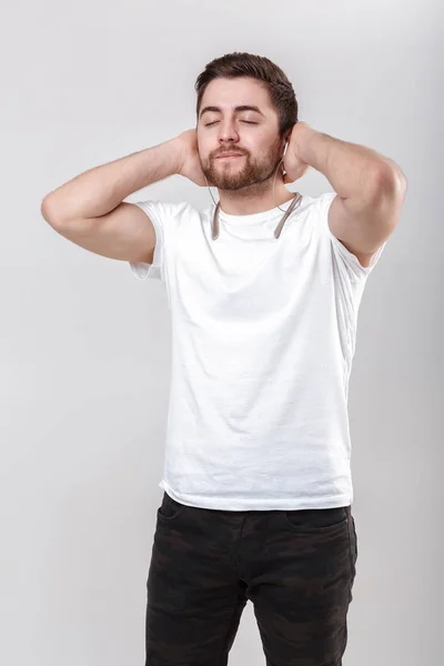 Giovane bell'uomo con la barba in t-shirt che ascolta musica con le cuffie — Foto Stock