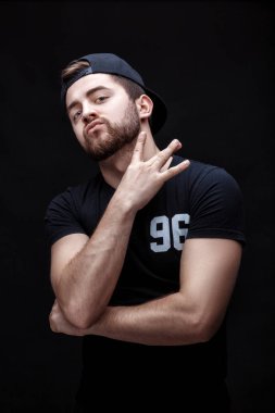 siyah gömlek ve siyah arka plan üzerine kap yakışıklı genç adam portresi. rapçi