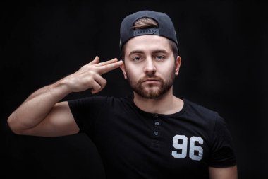 siyah gömlek ve siyah arka plan üzerine kap yakışıklı genç adam portresi. rapçi