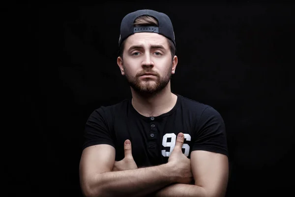 Retrato de joven guapo en camisa negra y gorra sobre fondo negro. rapero —  Fotos de Stock