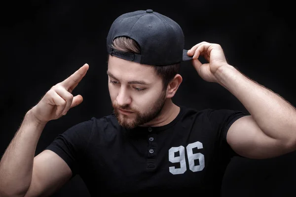 Retrato de joven guapo en camisa negra y gorra sobre fondo negro. rapero —  Fotos de Stock