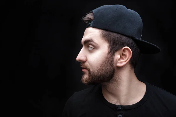 Retrato de joven guapo en camisa negra y gorra sobre fondo negro. rapero —  Fotos de Stock