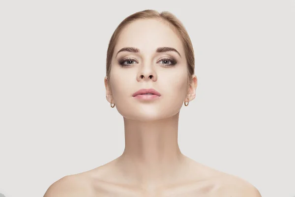 Retrato frontal de una hermosa joven con ojos verdes sobre fondo gris. chica con la piel limpia — Foto de Stock