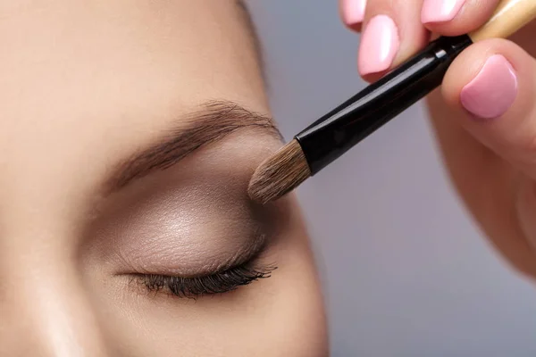 Trucco artista applicare pennello trucco per gli occhi. trucco per giovane ragazza. ombretto marrone. vicino — Foto Stock