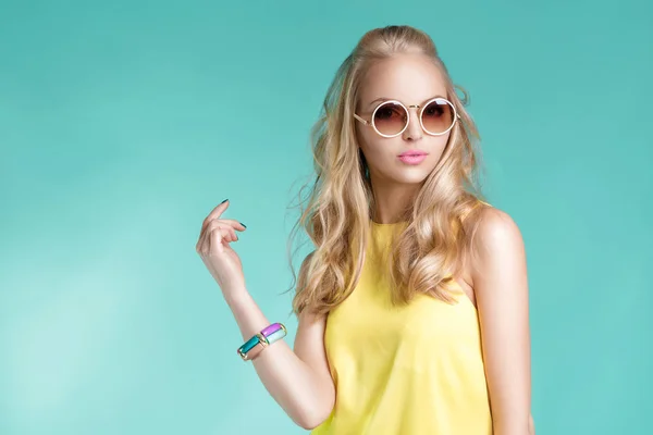 Portret piękne blond kobieta w okularach słonecznych i żółta koszulka na niebieskim tle. Beztroskie lata. — Zdjęcie stockowe