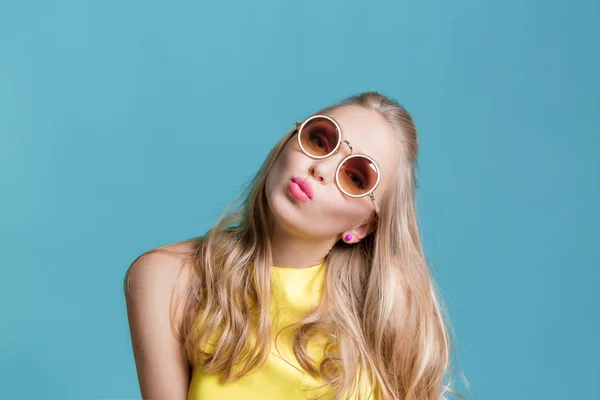 Portrait de belle femme blonde en lunettes de soleil et chemise jaune sur fond bleu. Été sans soucis . — Photo