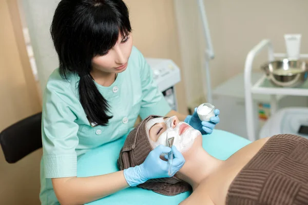Косметолог надевает маску на красивую молодую женщину в Спа салоне. косметическая процедура уход за кожей. Микродермабразия — стоковое фото