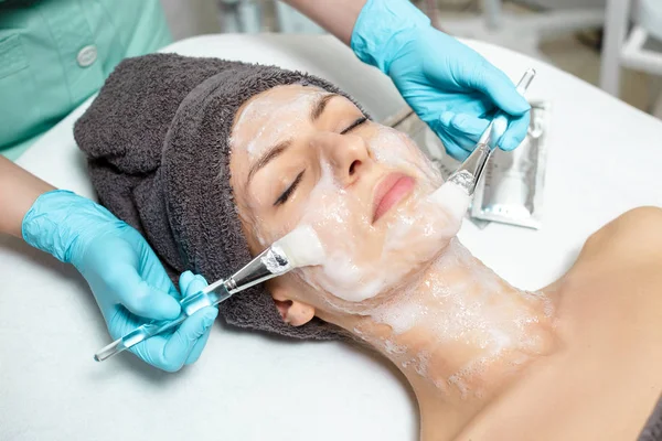 Esteticista aplica mascarilla en hermosa mujer joven en el salón de Spa. procedimiento cosmético cuidado de la piel. Microdermoabrasión — Foto de Stock