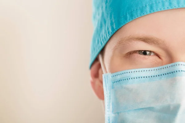 Manliga kirurg i mask blicken och tittar på kameran på grå bakgrund, närbild — Stockfoto