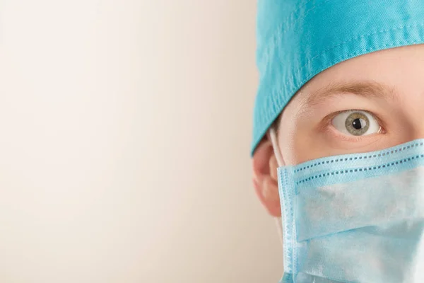 Verbaasd mannelijke chirurg in masker camera kijken op grijze achtergrond, close-up. kopie ruimte — Stockfoto