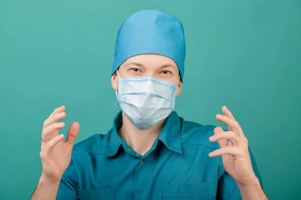 Manliga kirurg i mask tittar på kameran på blå bakgrund, närbild — Stockfoto