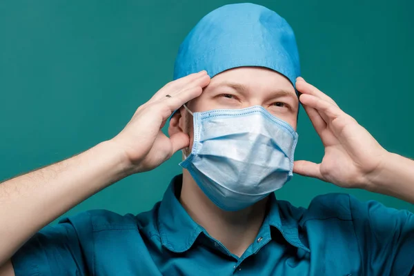 Moe mannelijke chirurg in masker op blauwe achtergrond, close-up — Stockfoto
