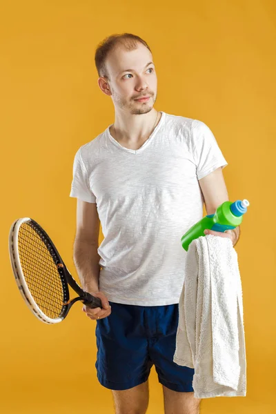 Jonge tennisser met handdoek bedrijf tennisracket op gele achtergrond — Stockfoto