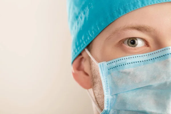 Manliga kirurg i mask tittar på kameran på grå bakgrund, närbild — Stockfoto