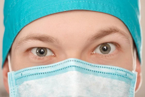 Manliga kirurg i mask tittar på kameran på grå bakgrund, närbild — Stockfoto