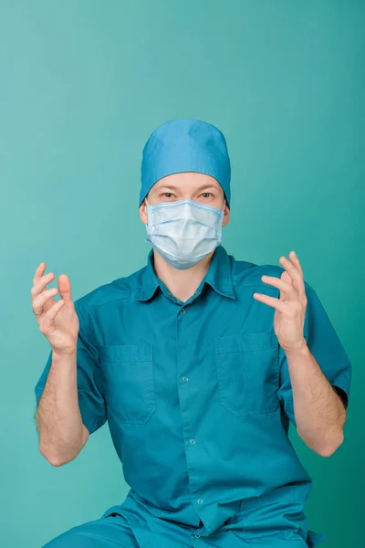 Хирург в маске смотрит на камеру на синем фоне, закрывается — стоковое фото
