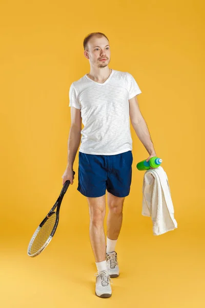 Jovem tenista com toalha segurando raquete de tênis no fundo amarelo — Fotografia de Stock